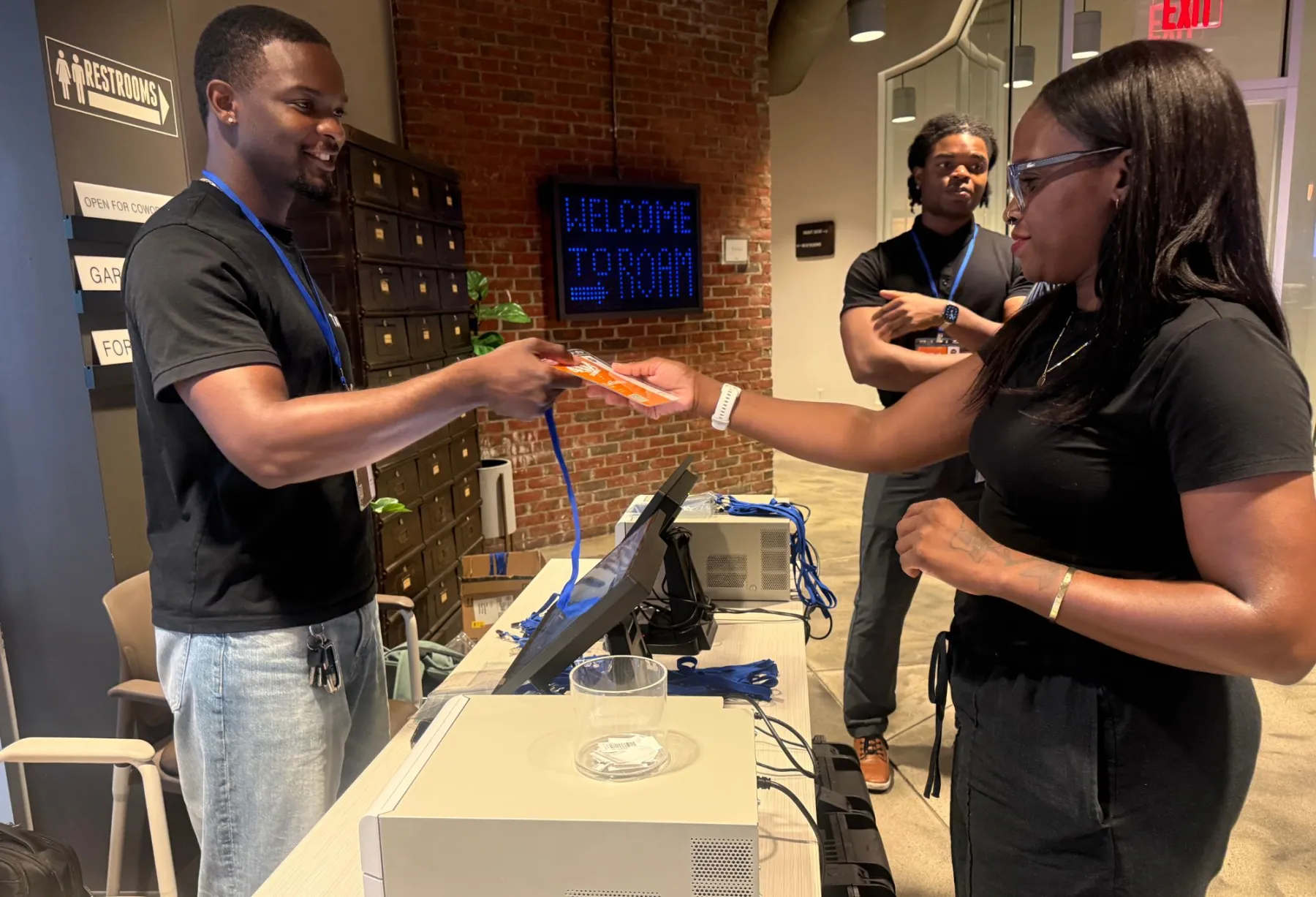 A TAPN crew member hands a freshly printed badge to an attendee at the check-in table